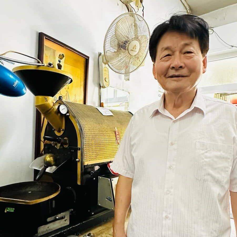 コーヒーロースターの隣に立つ男性